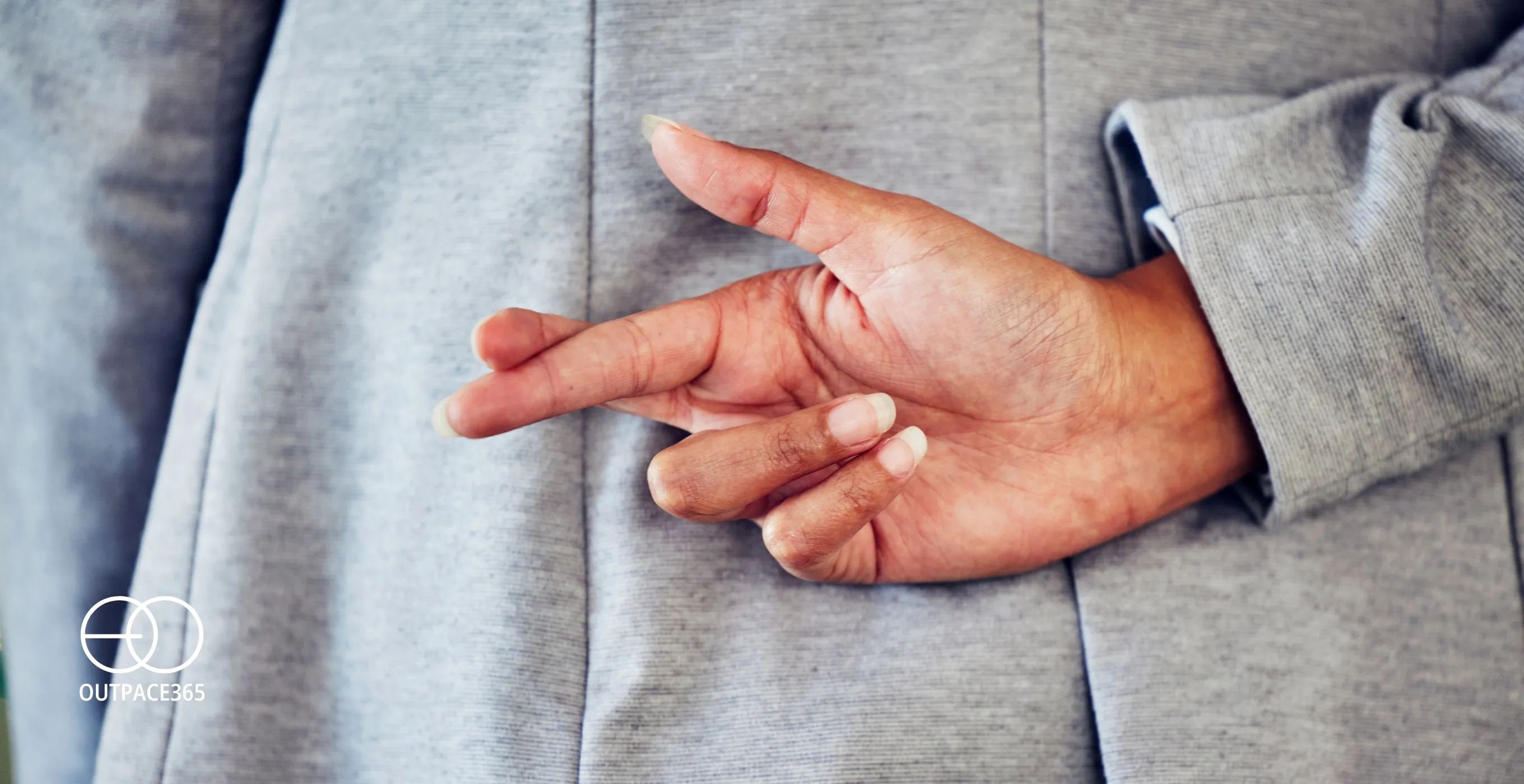 A man in a suit holding his fingers crossed behind his back