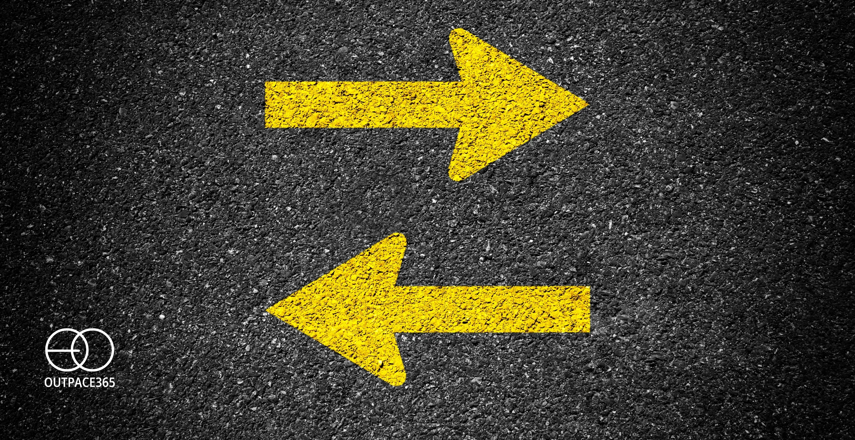 Two yellow arrows painted on asphalt, pointing opposite ways