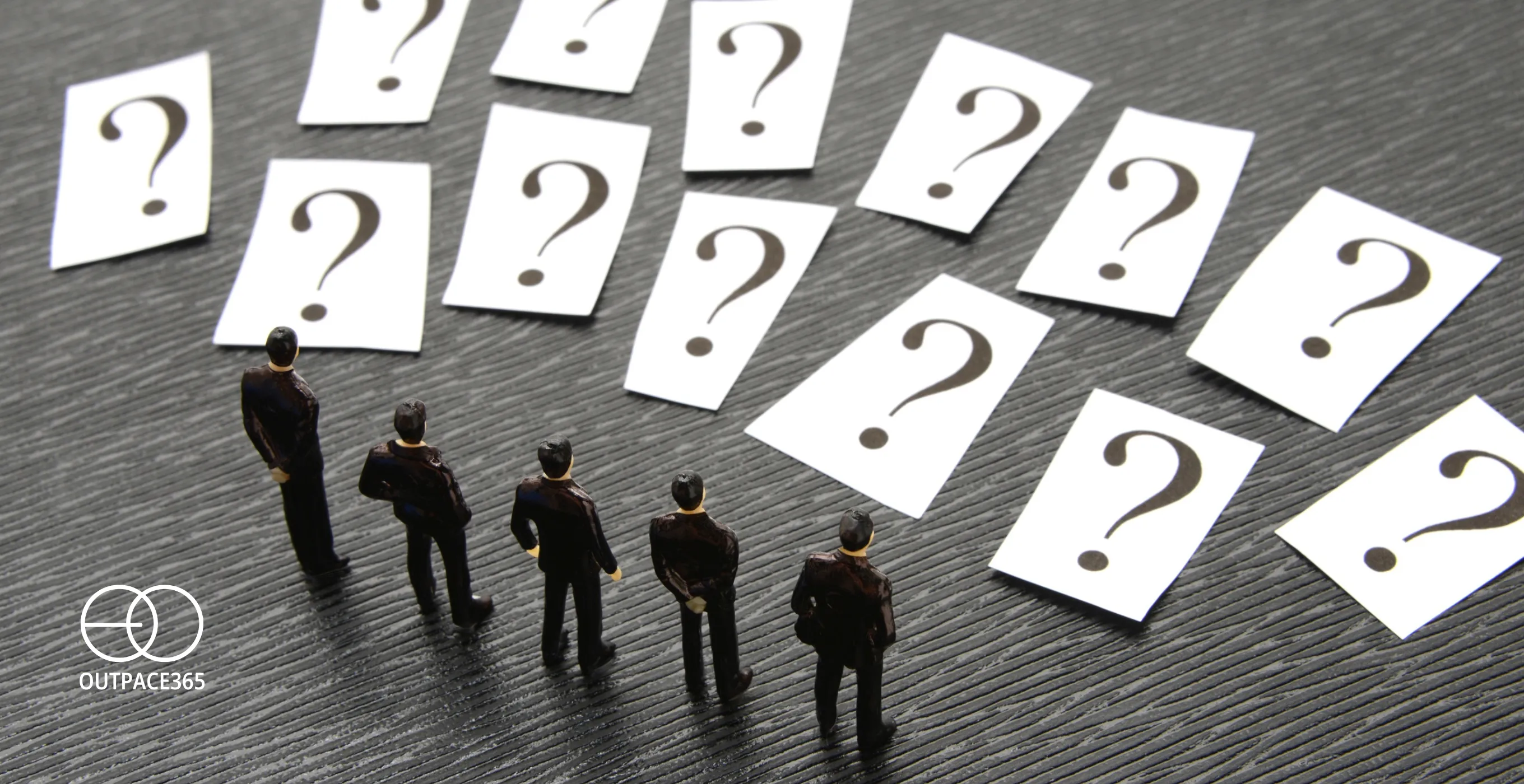 Miniature figures facing a wall of question-mark cards